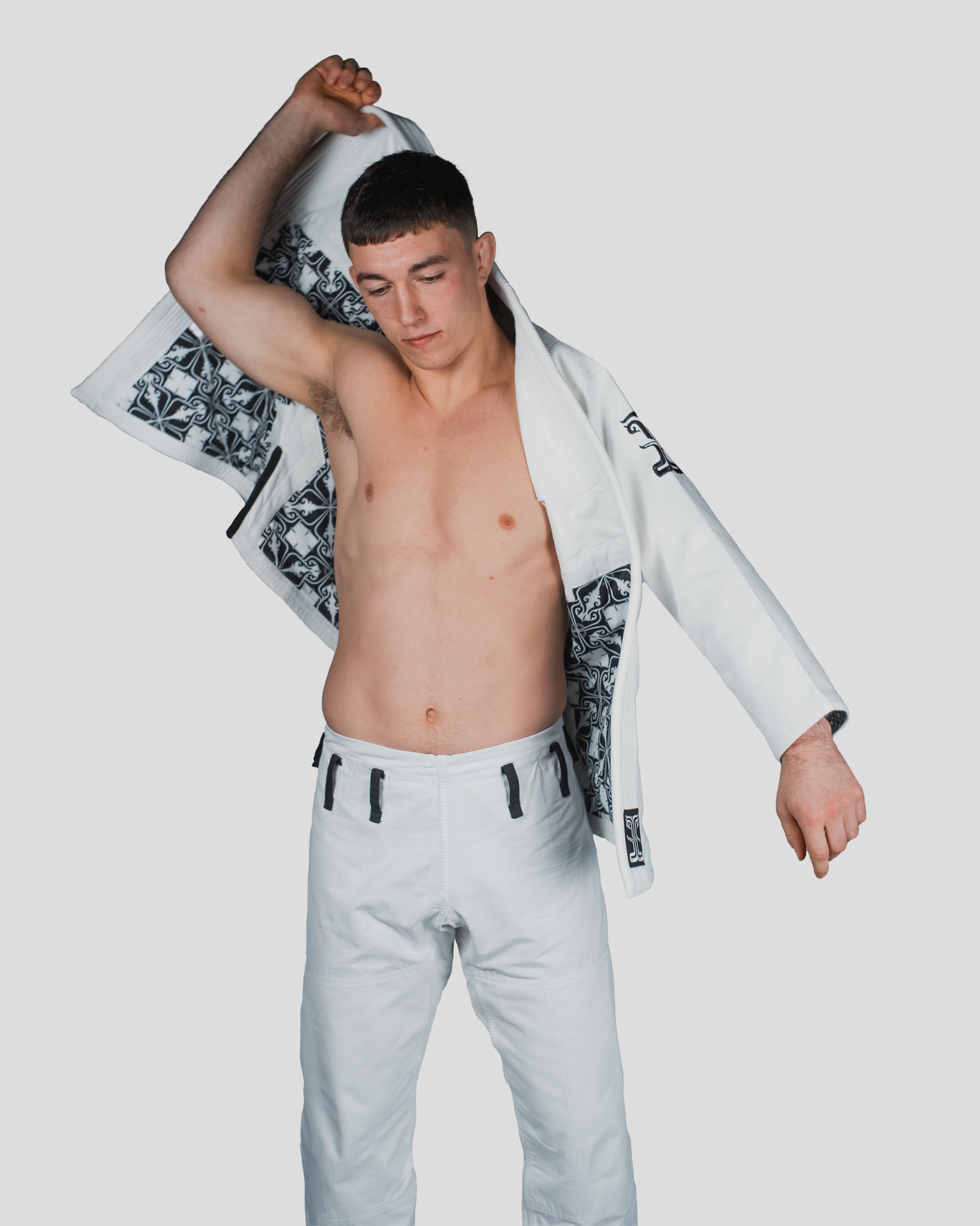 Male athlete in motion, putting on the Guile Gi, emphasizing the movement-friendly fit and interior details