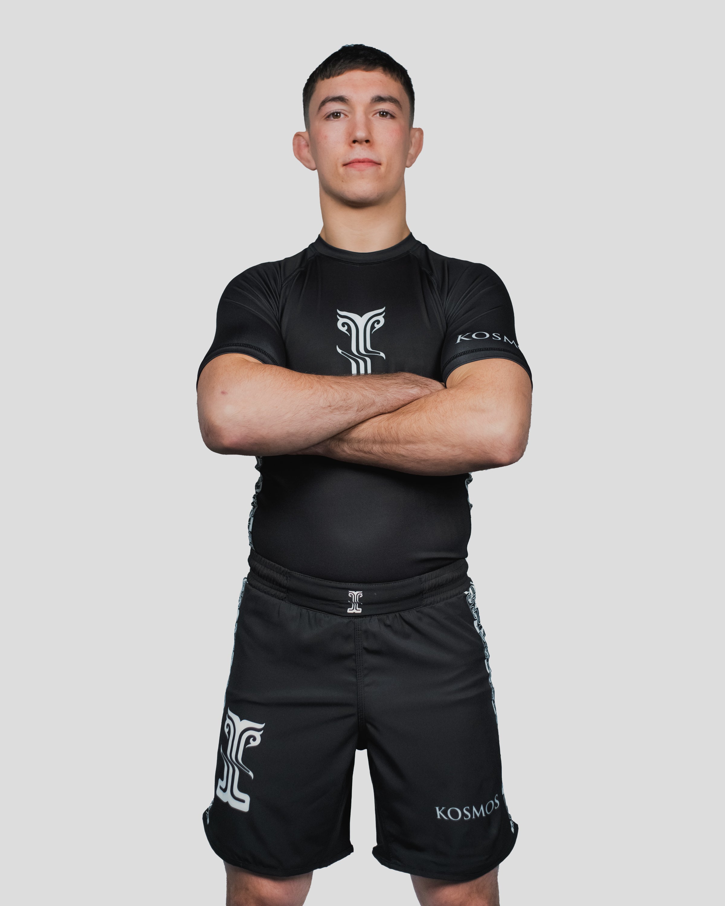 Male athlete standing confidently with arms crossed in the Persist Guard Short Sleeve, designed for durability and flexibility in combat sports