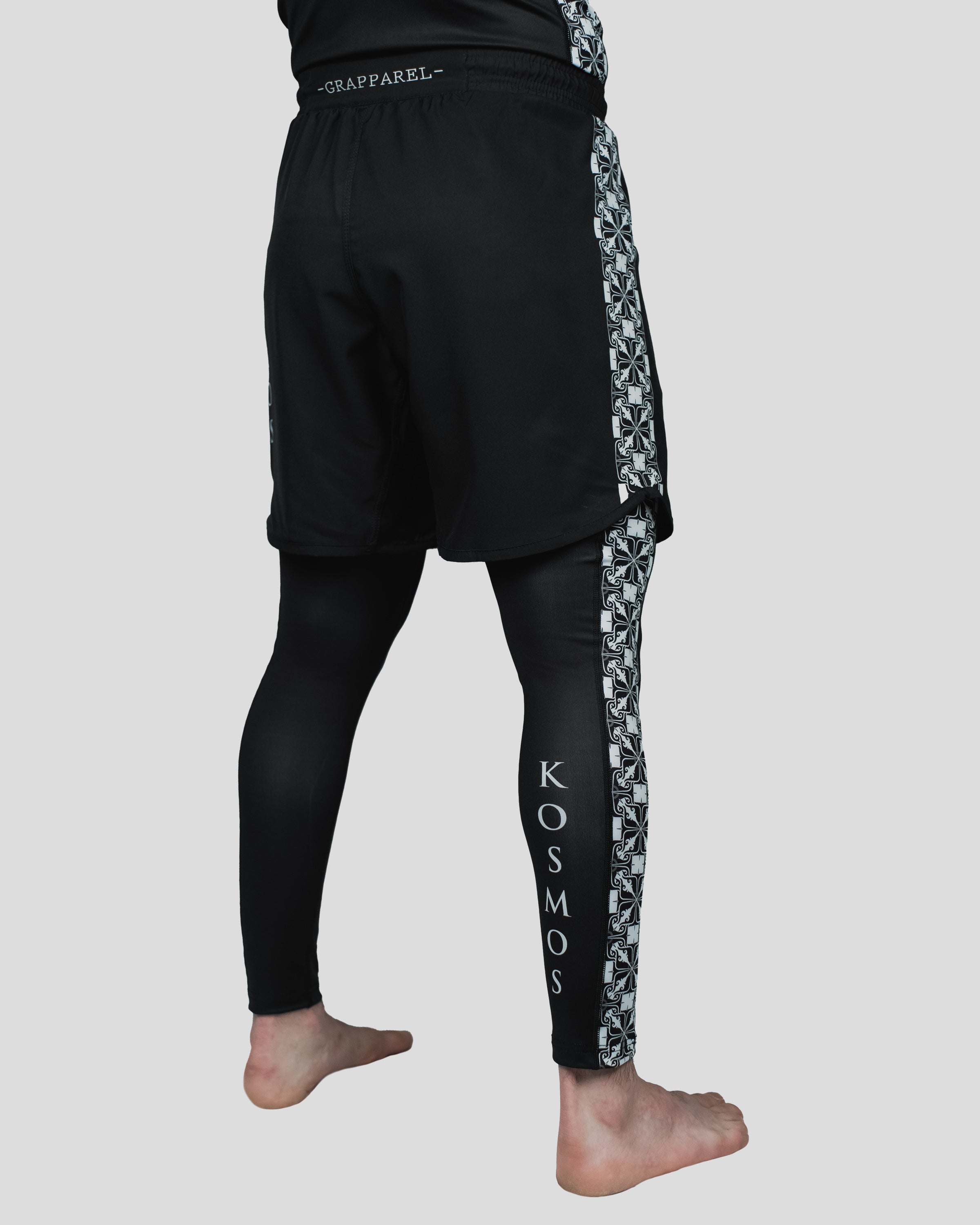 Back view of Persist Spats worn under black Kosmos training shorts, featuring bold side patterns and Kosmos branding on the calf