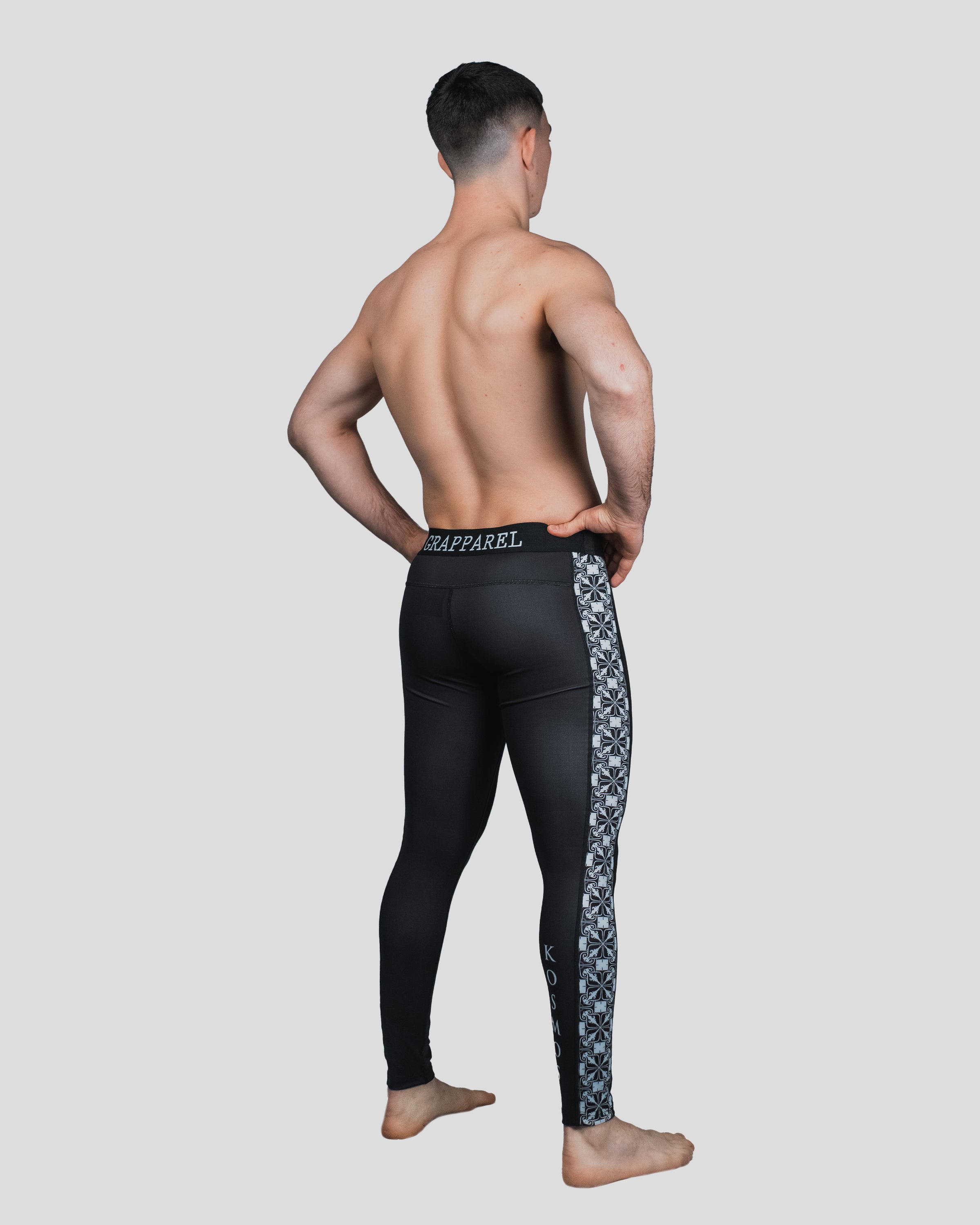 Rear view of a male athlete wearing Persist Spats, showcasing the sleek black design with intricate white side detailing