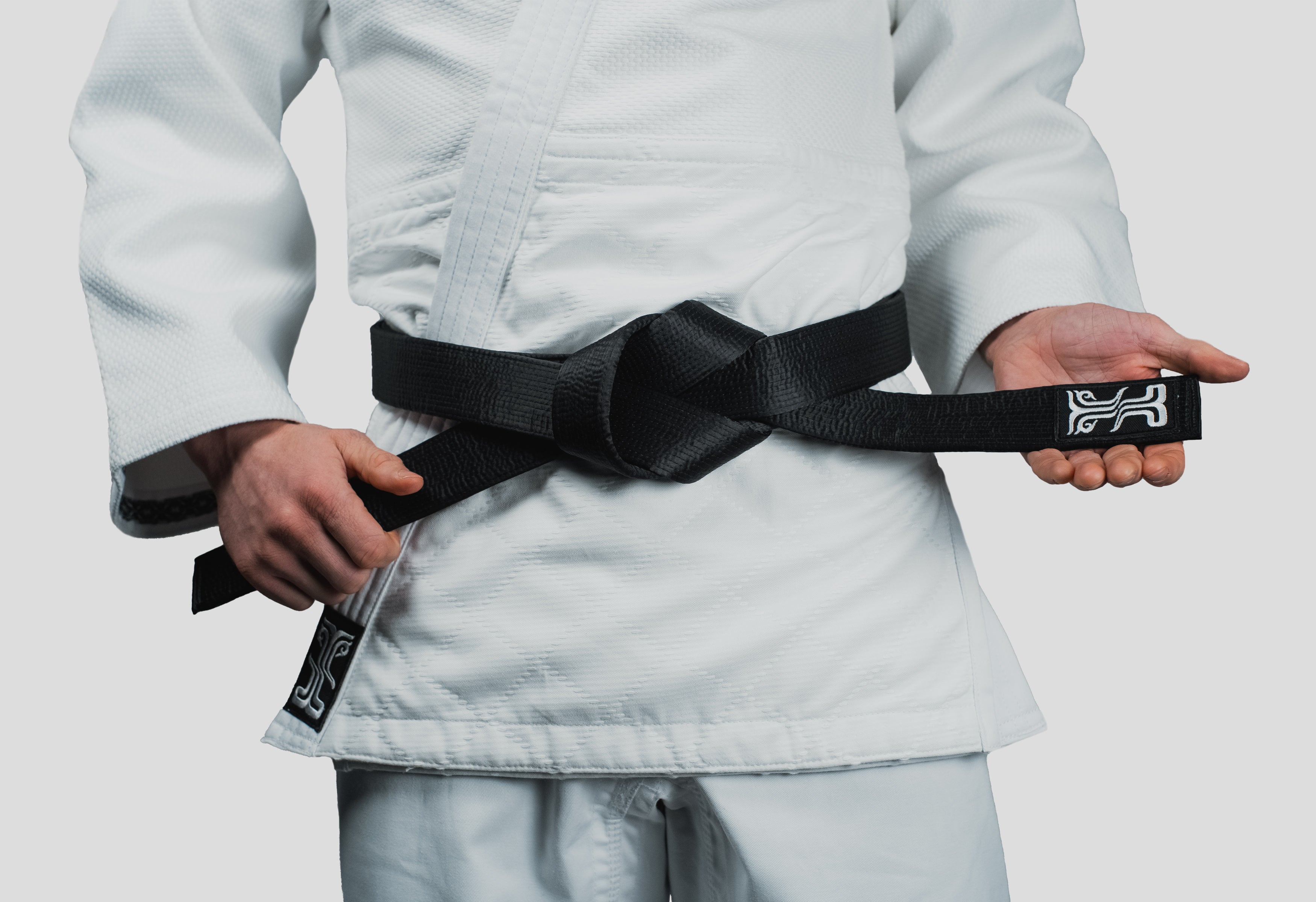 Phobos Black Judo Belt securely tied around a Kosmos gi, showcasing the belt's premium fabric and traditional knot style