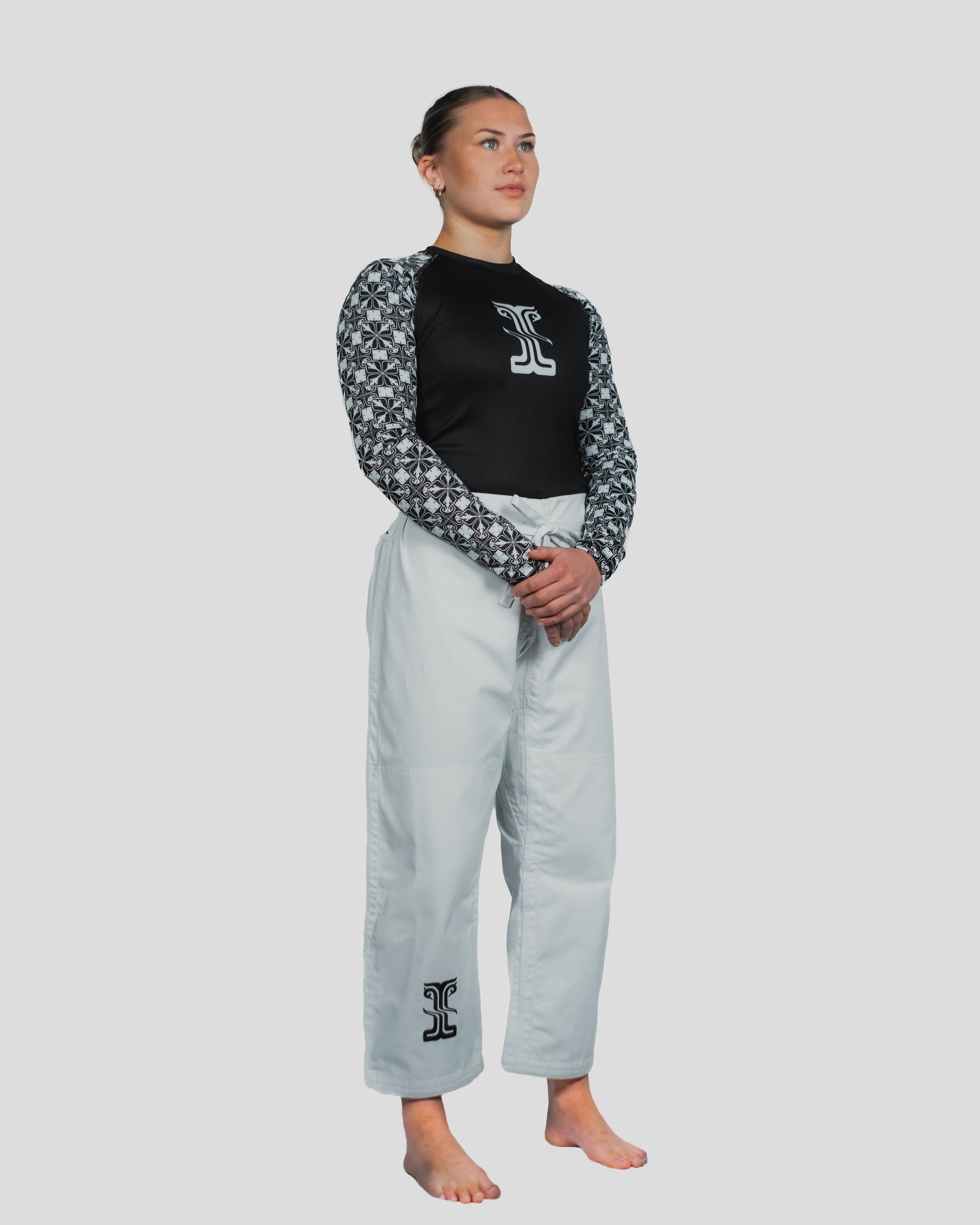 Female martial artist wearing Kosmos rash guard and Stoa Gi Women's Judo pants, featuring black and white pattern sleeve design