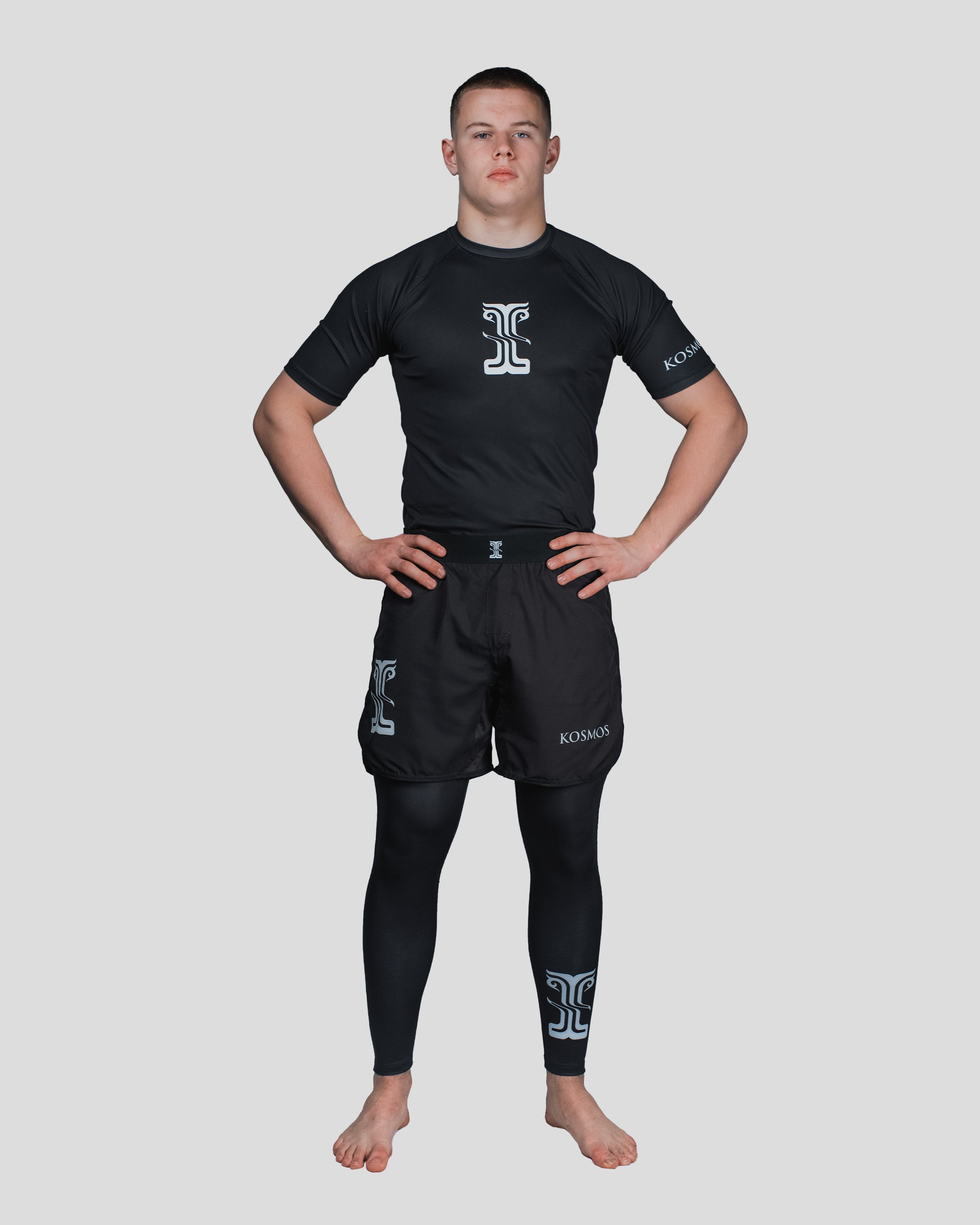 Full-body shot of a male athlete wearing the Column Guard short sleeve rash guard, paired with matching shorts and spats