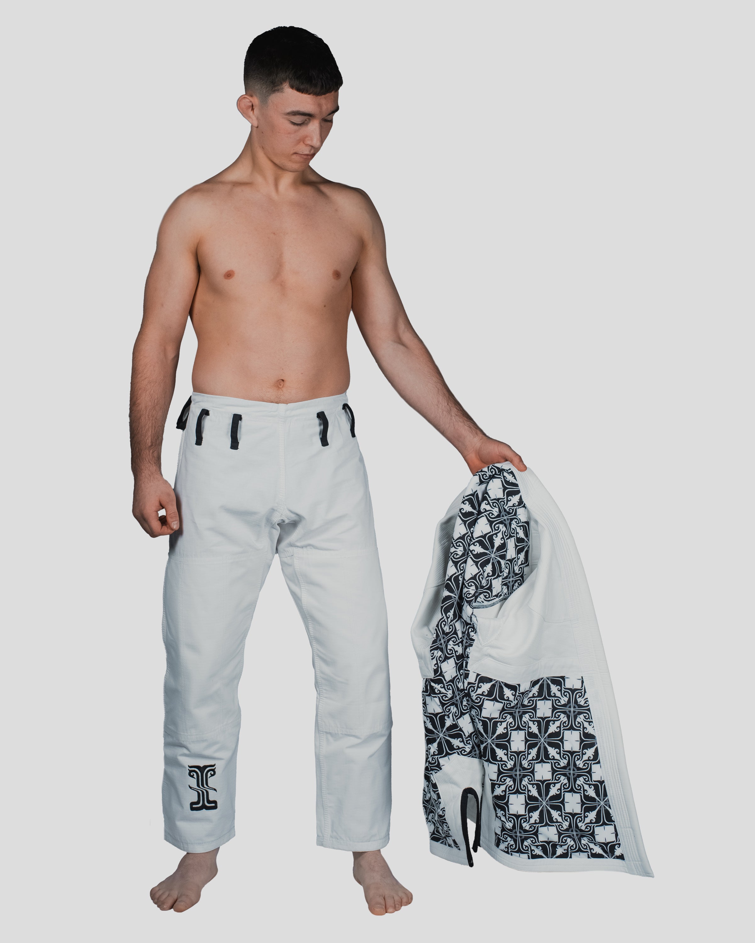 Male athlete holding open the Guile Gi jacket to reveal the bold black-and-white patterned inner lining