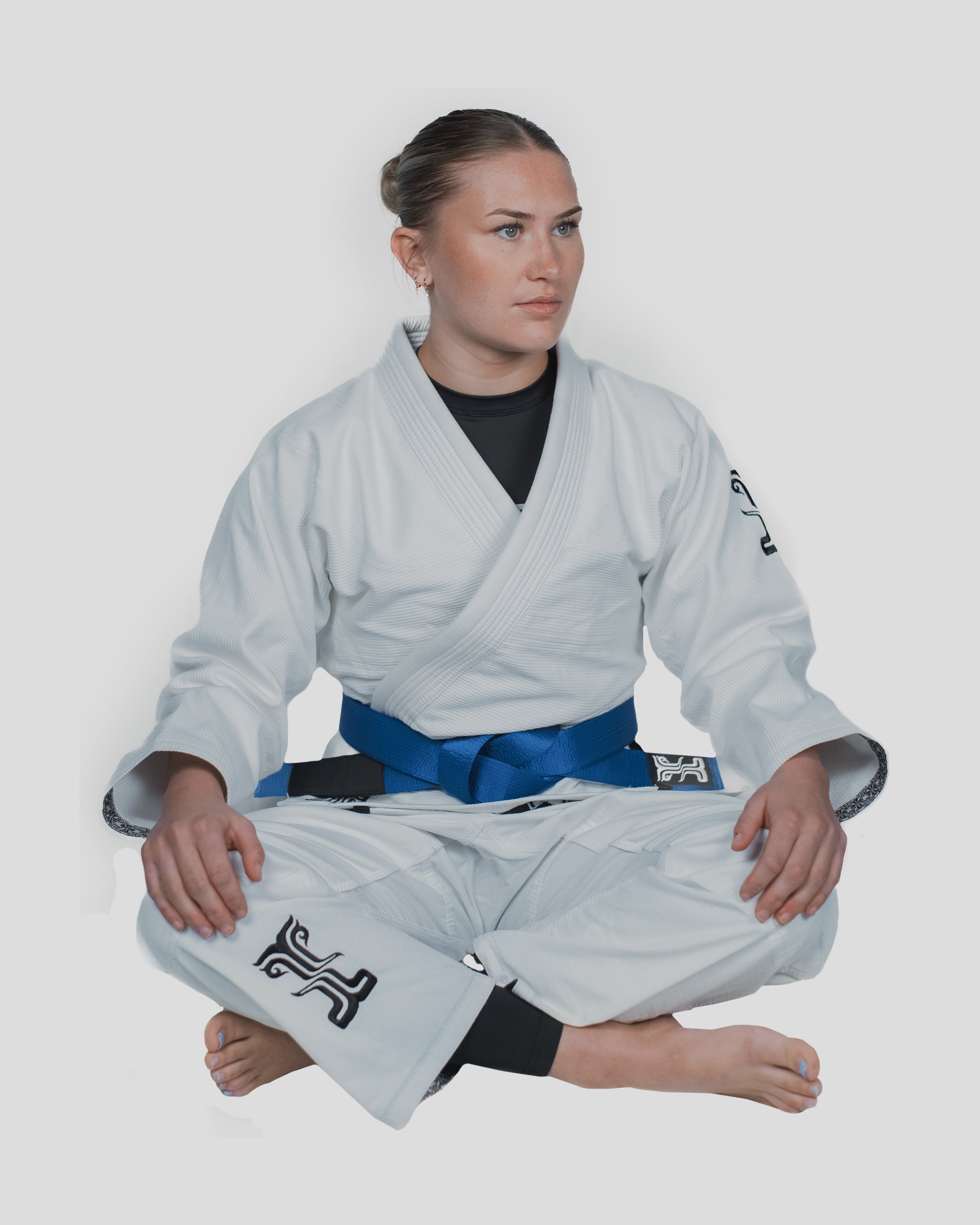 Woman seated in the Guile Women's Jiu Jitsu Gi, showcasing the comfortable fit and flexible design for grappling and training