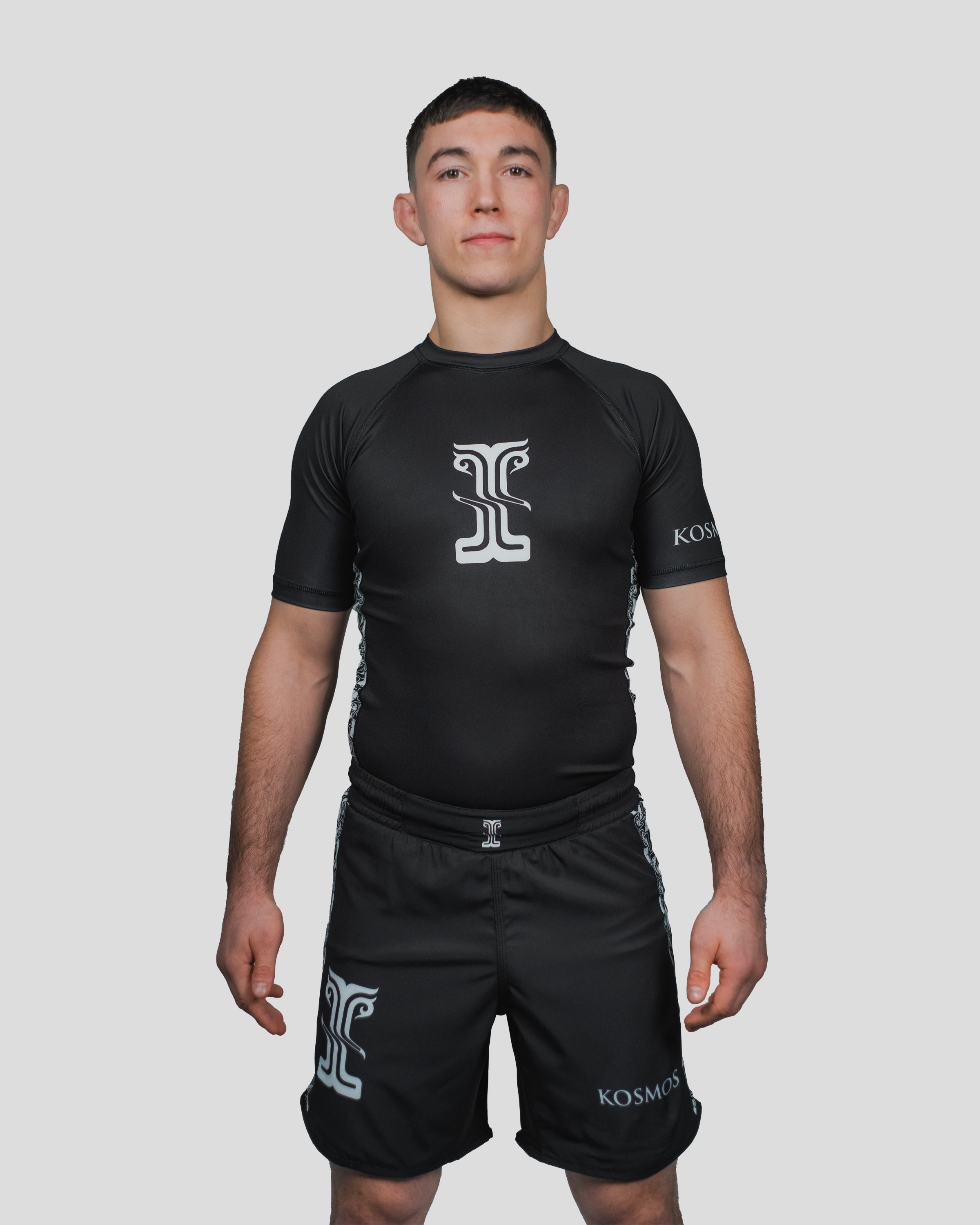Front-facing image of the Persist Guard Short Sleeve, highlighting the sleek black design and Kosmos branding for high-performance training