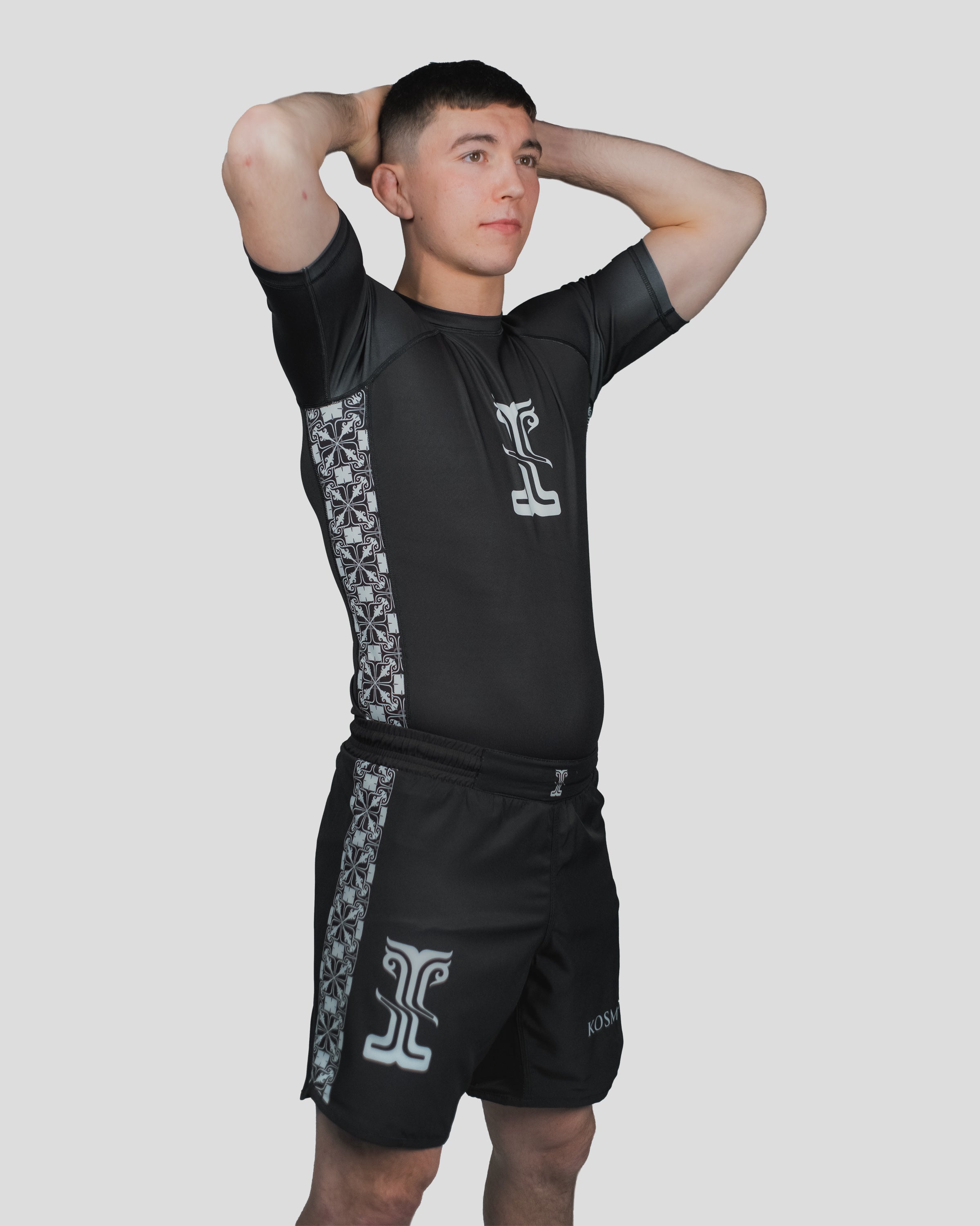 Athlete wearing the Persist Shorts and Rash Guard, featuring a sleek black design with Kosmos pattern accents