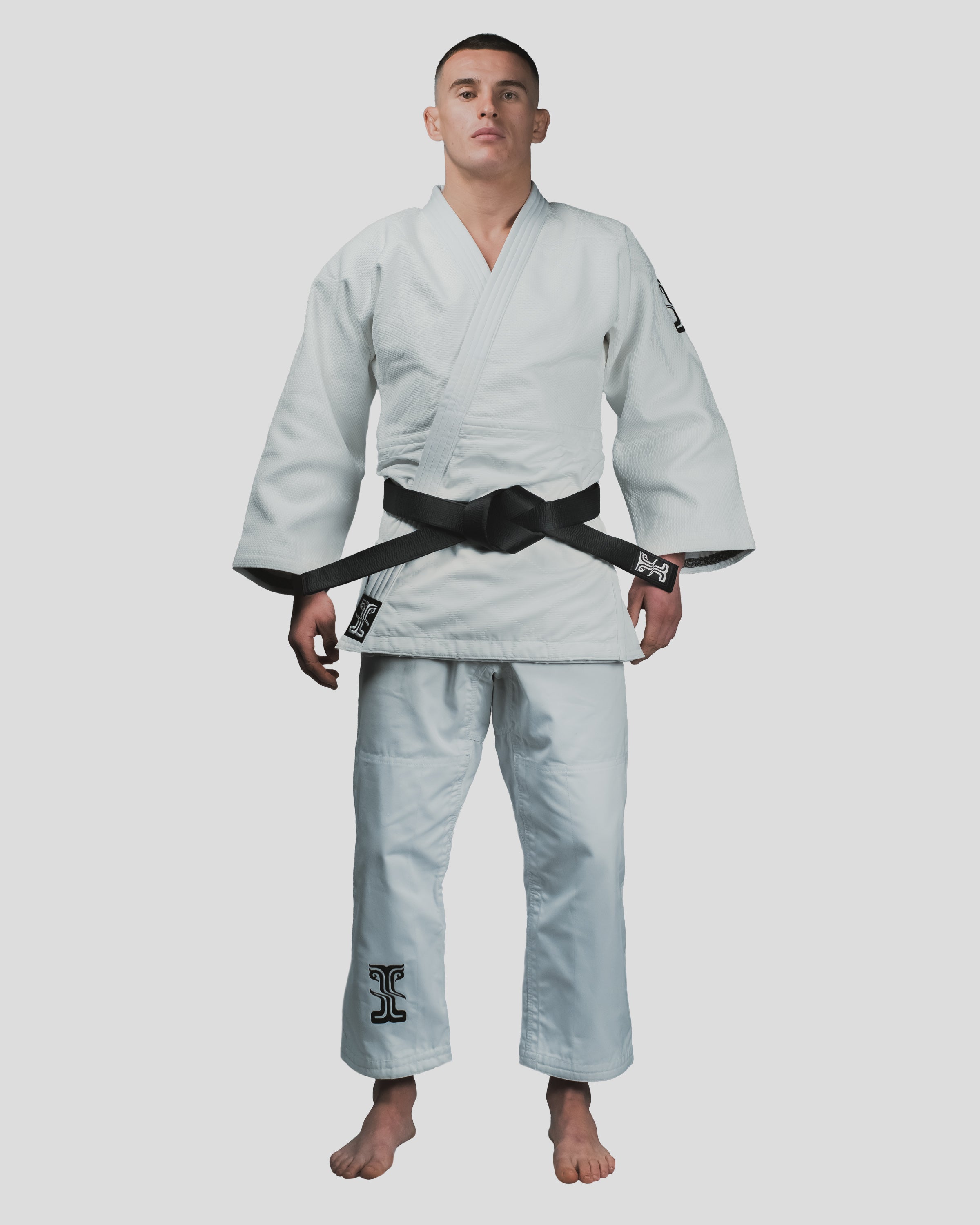 Full-body front view of the Stoa Gi Men's Judo uniform, worn with a black belt, highlighting the clean-cut fit and reinforced design